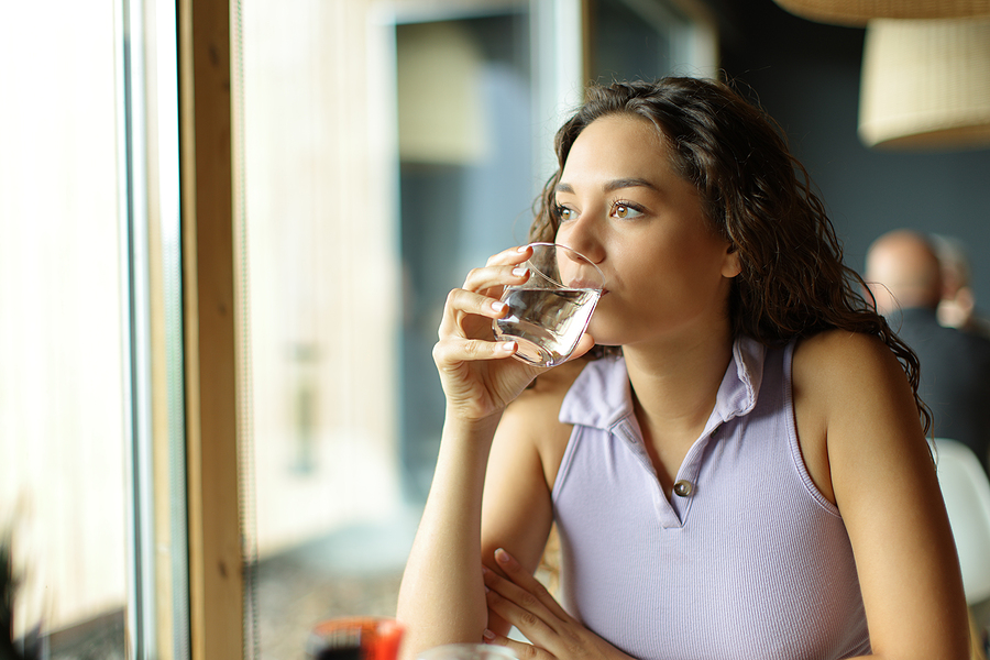 Distracted Woman Drinking Water In A Restaurant Looking Away Thr