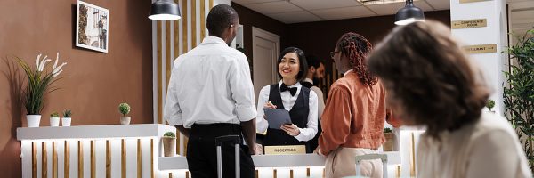 Hotel Staff Registering People At Resort, Filling In Records At