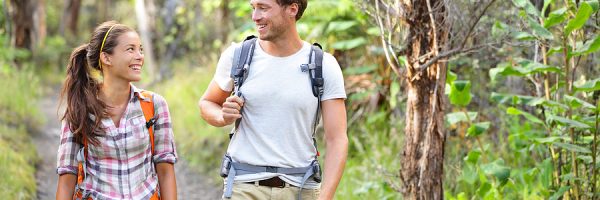 Hikers hiking people walking happy in forest. Hiker couple lau